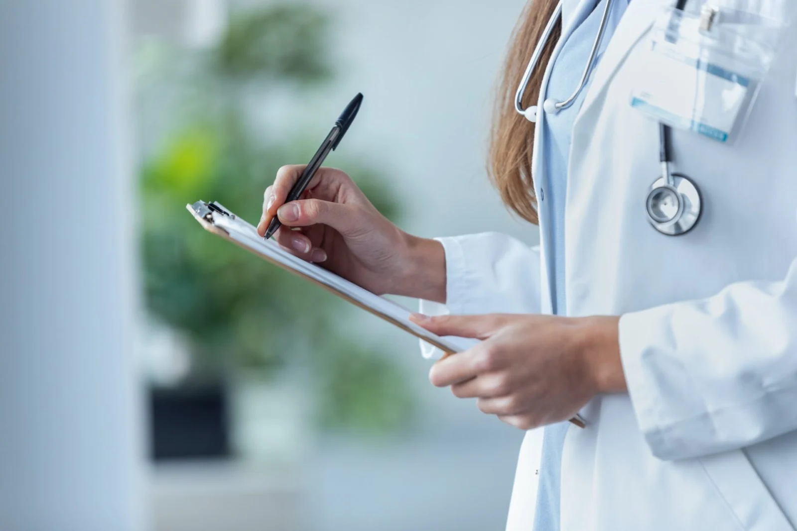 Médica llenando un formulario en una tabla de apuntes